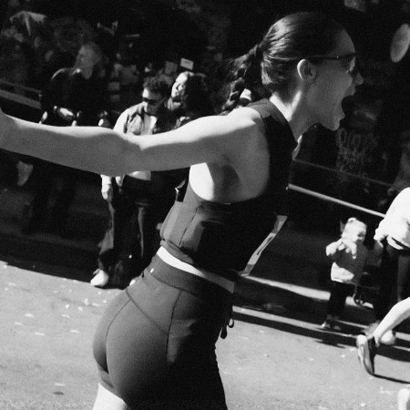 Black and white photo of a woman in athletic wear, mid-stride, with her mouth open and arm outstretched.