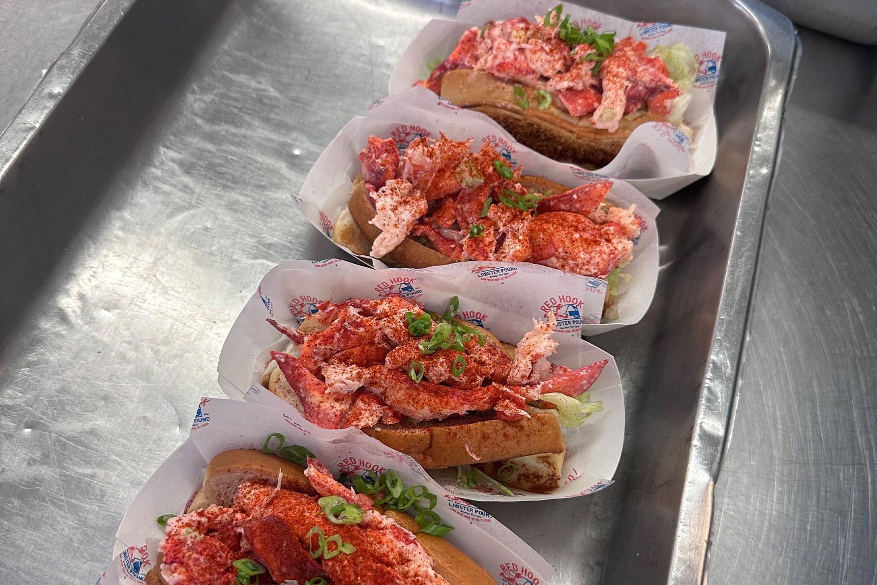4 maine lobster rolls in paper boats in a silver tray