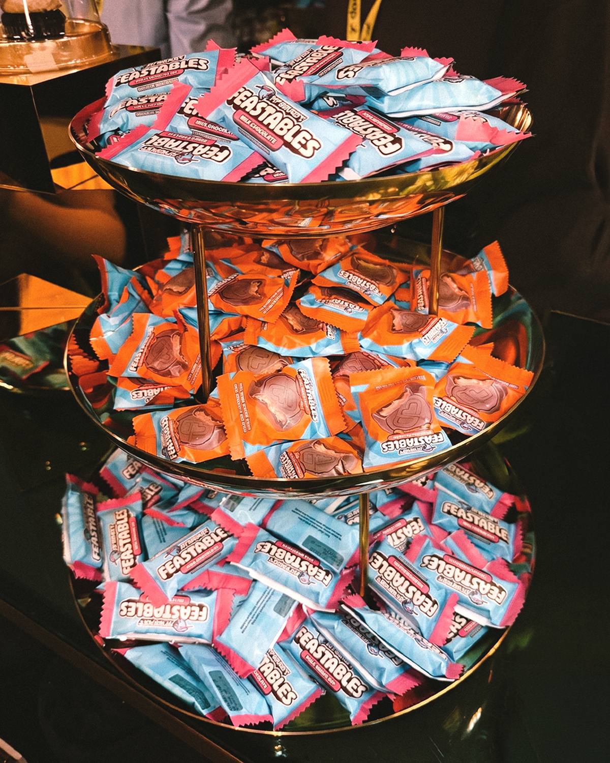 A three-tiered stand filled with Feastables chocolates in light blue and orange wrappers.