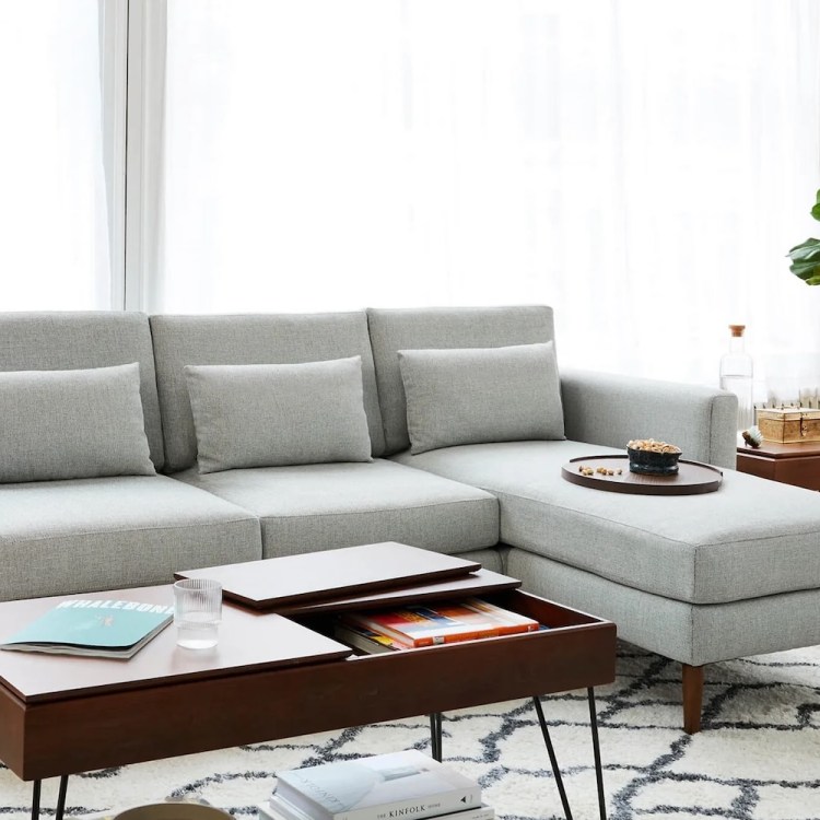 Light gray sectional sofa with a chaise lounge, a dark wood coffee table with storage, and a fiddle-leaf fig plant