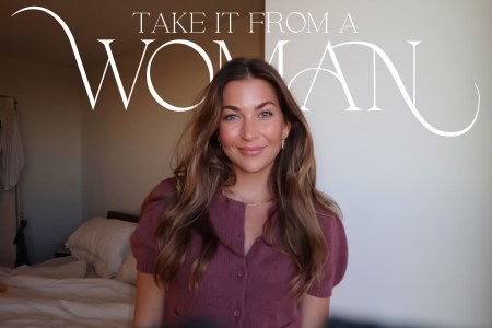 Smiling woman with long brown hair in a pink cardigan, with "TAKE IT FROM A WOMAN" text overlay.