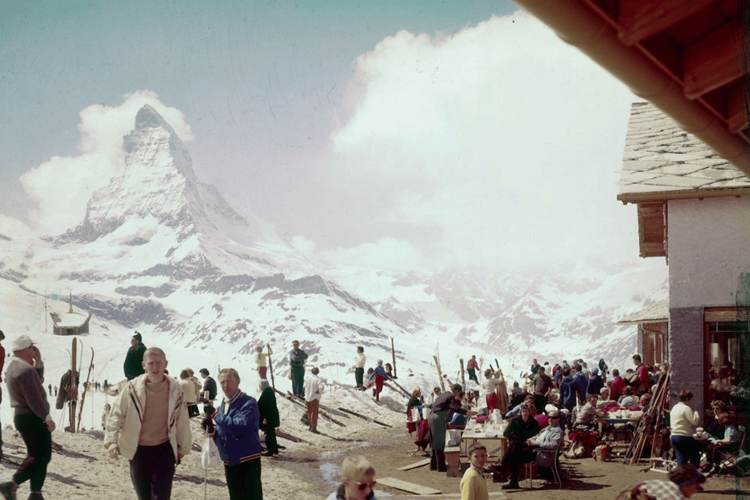 Skiers and mountain climbers gather at a snowy resort with the Matterhorn peak in the background.
