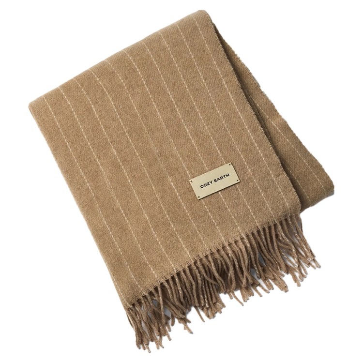 Folded tan blanket with thin white pinstripes, fringe on one end, and a "COZY EARTH" label.