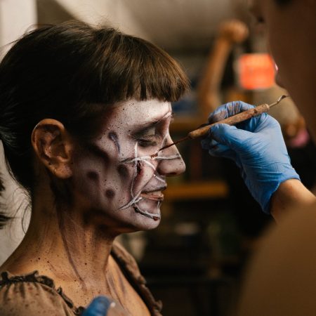 a woman with bangs getting a pentagram painted on her face for halloween