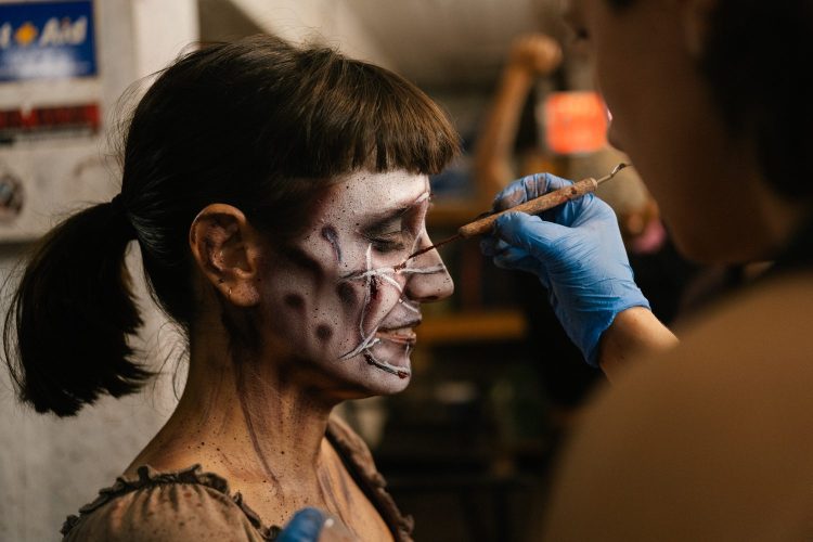 a woman with bangs getting a pentagram painted on her face for halloween