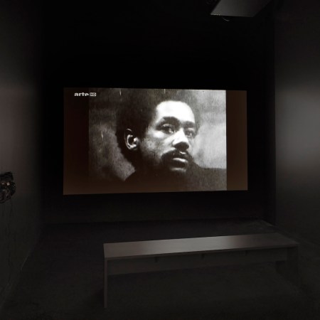 Photo of a Black man in a dark room with a bench and headphones