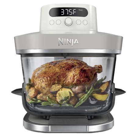 A Ninja Foodi Smart XL air fryer oven with a whole roasted chicken and vegetables inside.