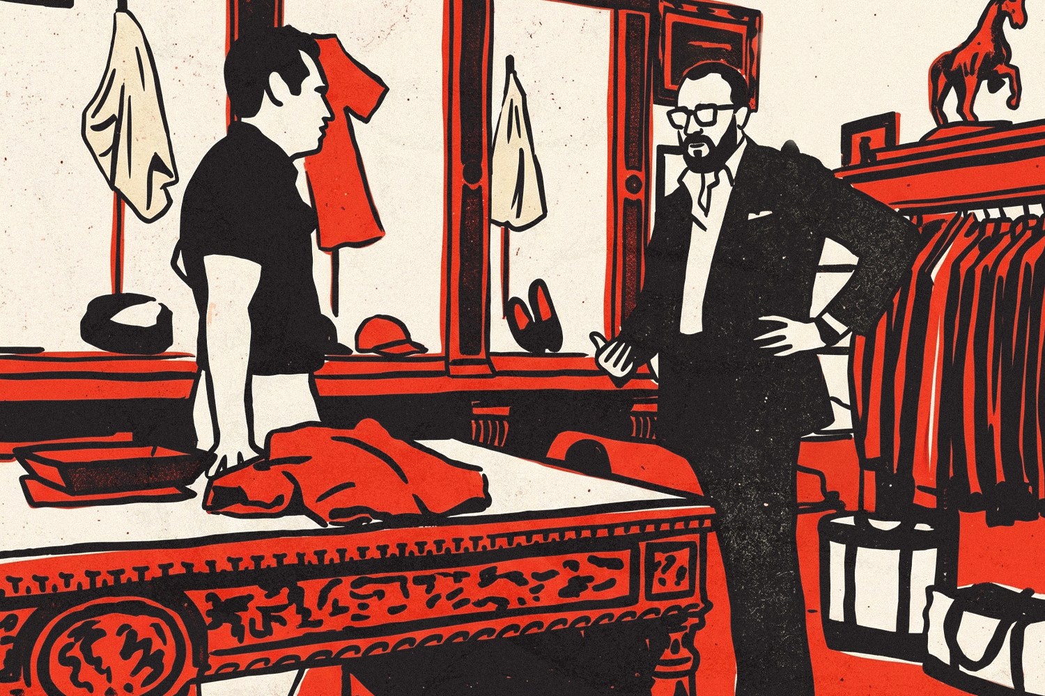 A man in a suit gestures to a man in a polo shirt over a table with clothes in a red and black shop.