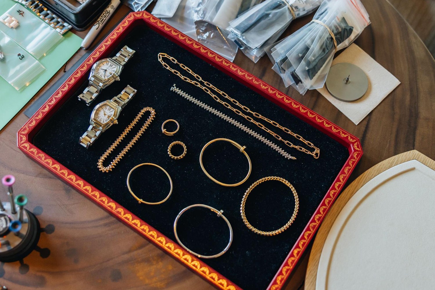 Luxury jewelry, including two watches, necklaces, rings, and bracelets, displayed on a black velvet tray.