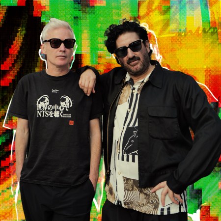 Two men in sunglasses, one with white hair and one with a beard, pose against a vibrant, glitchy background.