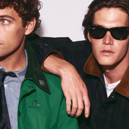 Two men in jackets with corduroy collars, one in green with a tie, the other in plaid with sunglasses.
