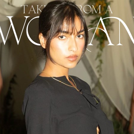 A woman with dark hair and bangs in a black top looks at the viewer, with two blurred models behind her.